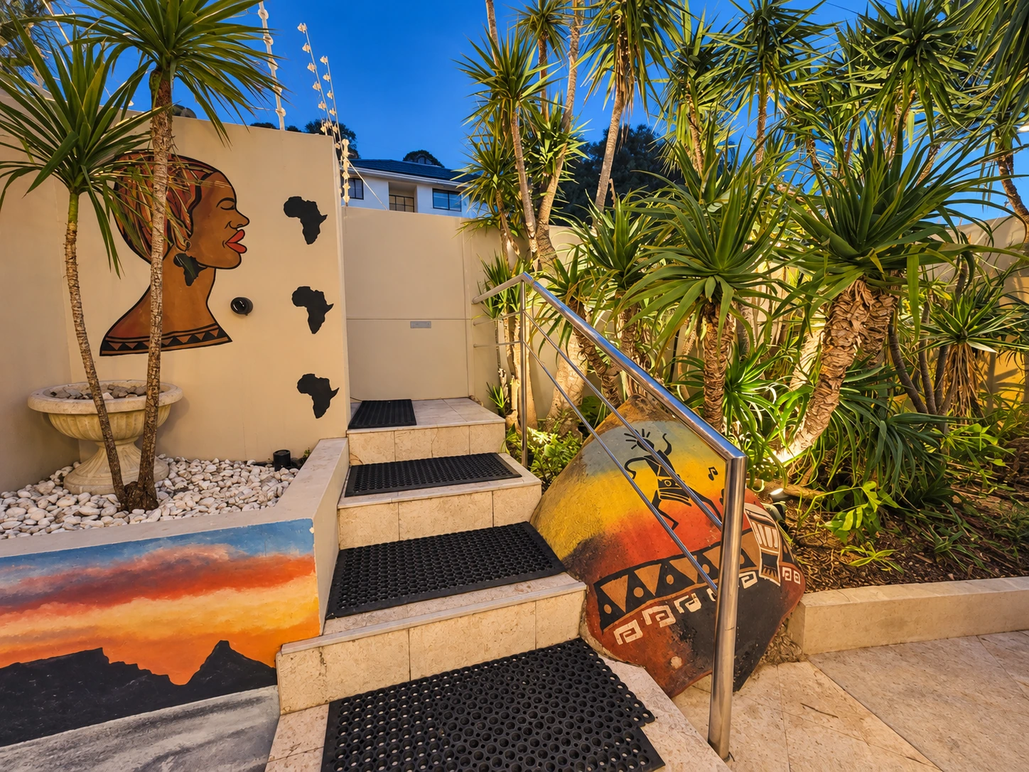 Garden entrance steps with African artwork at dusk